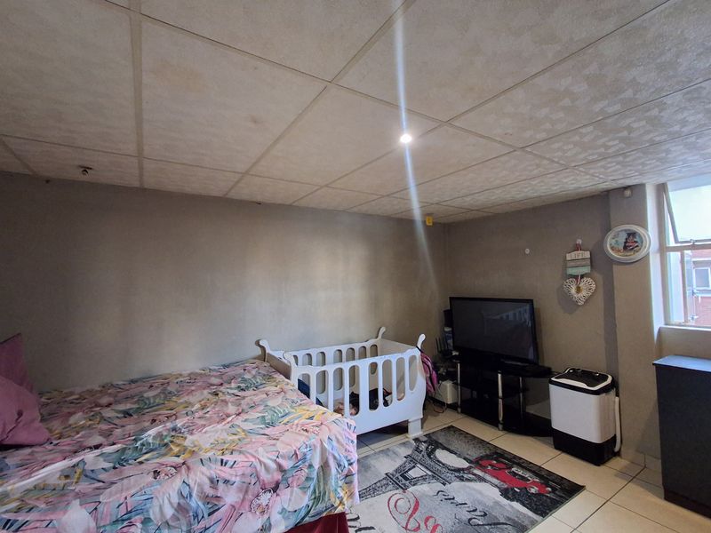 A bedroom featuring tiled flooring and a drop ceiling. The space requires cosmetic updates to improve the overall finish and aesthetic appeal.