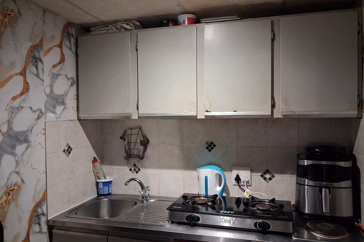 A compact kitchen area featuring a stainless steel sink, built-in cabinetry, tiled backsplash, and a gas cooktop.