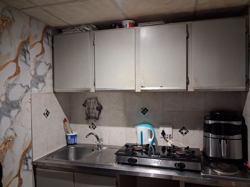 A compact kitchen area featuring a stainless steel sink, built-in cabinetry, tiled backsplash, and a gas cooktop.