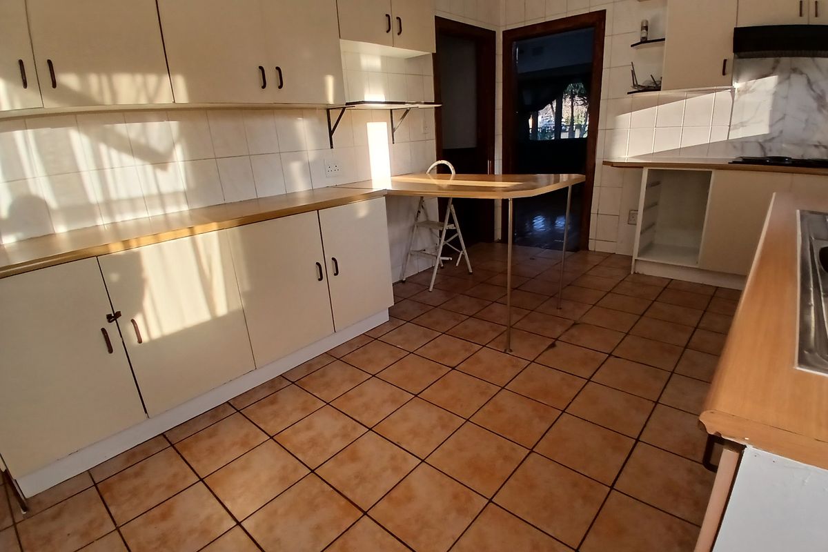 A dated kitchen featuring laminate countertops, tiled flooring, and ample built-in cabinetry, offering a functional layout ready for modern renovation.