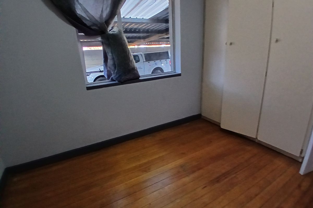 A vacant bedroom featuring polished timber flooring and built-in storage cupboards, offering a clean canvas for potential interior updates.
