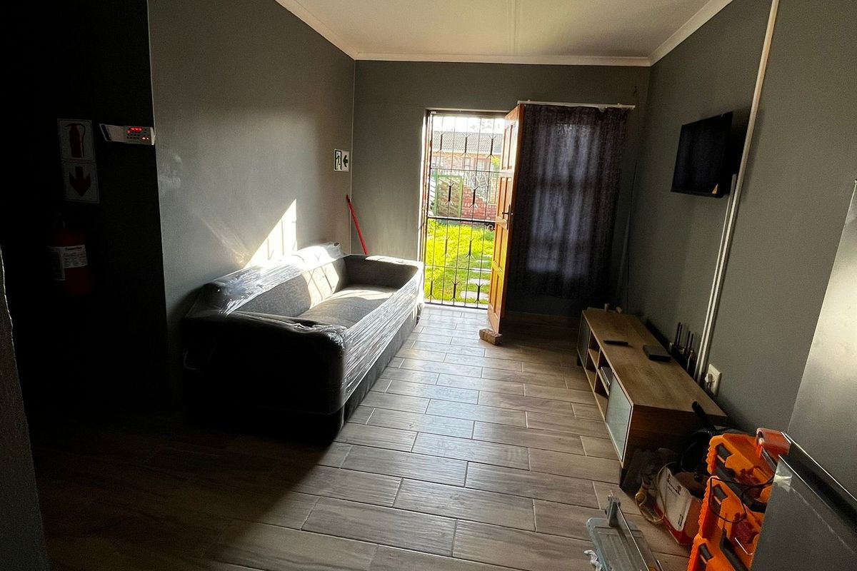 A living room featuring tiled flooring and direct access to the rear garden through a security gate.