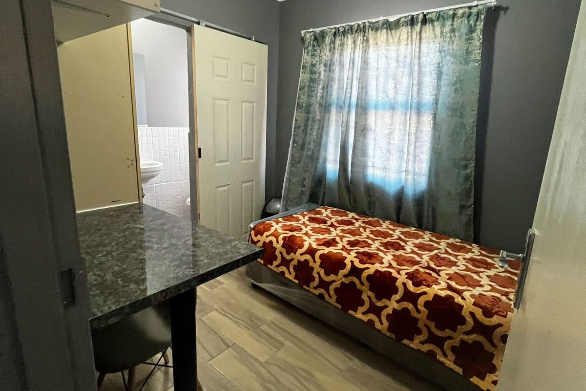 A compact bedroom featuring laminate flooring, a built-in desk area, and direct access to an en-suite bathroom.