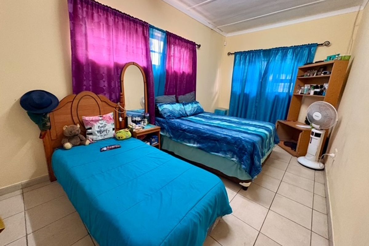 A bedroom featuring tiled flooring, built-in curtain rods, and neutral wall finishes, providing a functional space for rest.