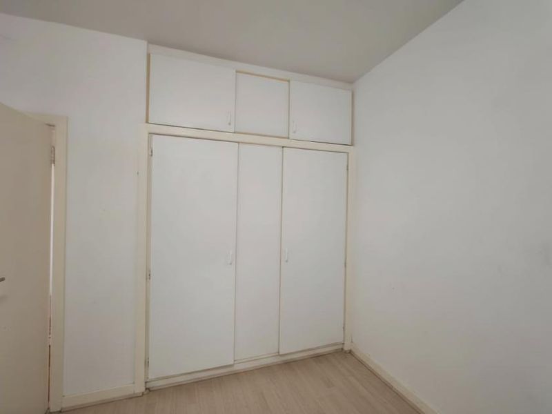 A vacant bedroom featuring white built-in wardrobes with overhead storage and light-toned laminate flooring.
