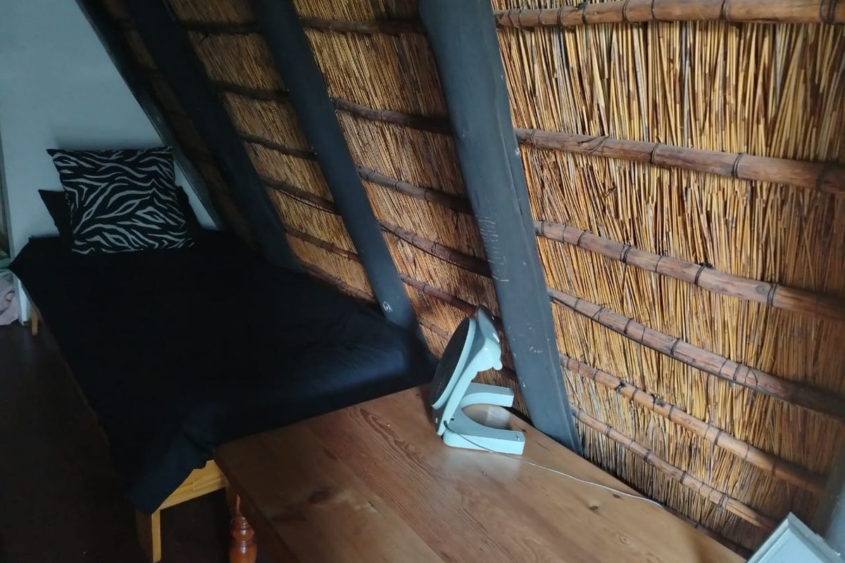 A cozy bedroom featuring a unique pitched ceiling with exposed timber rafters and traditional thatched roofing.