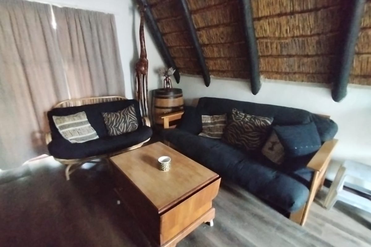 A cozy living room featuring a traditional thatched roof with exposed timber rafters and modern laminate flooring.