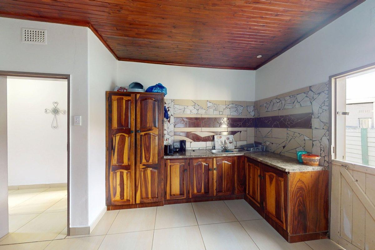 A dated kitchen featuring wooden cabinetry, stone countertops, a tiled splashback, and a distinctive wooden ceiling, offering potential for a modern renovation.