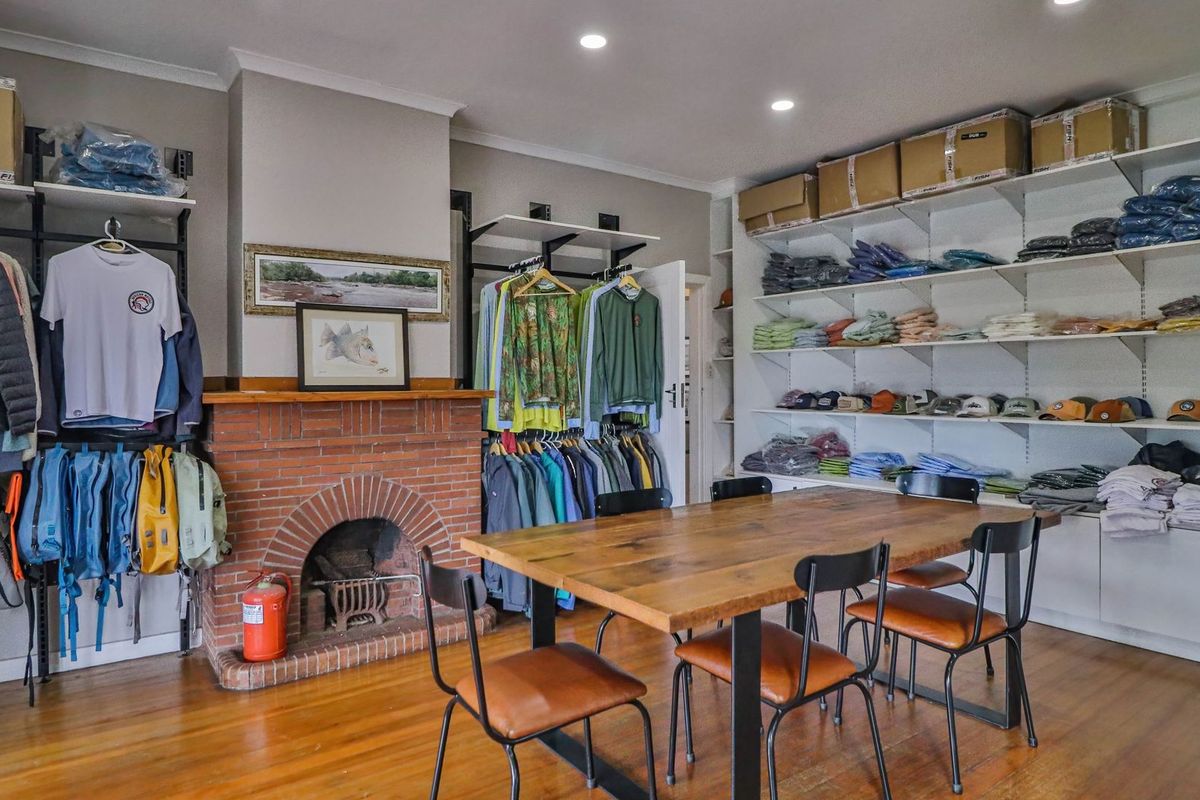 A living area featuring a classic brick fireplace, timber flooring, and extensive built-in shelving, currently utilized as a retail display space.