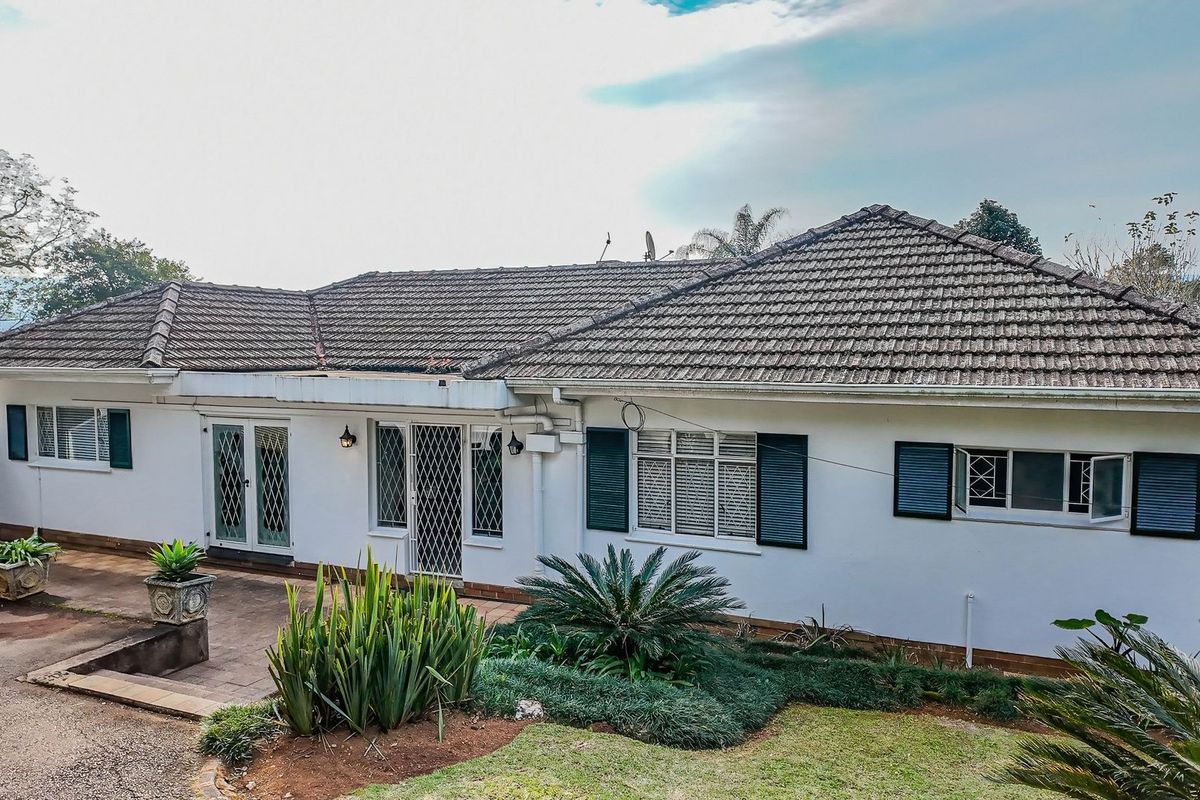 Rear view of a single-story house featuring a tiled roof, paved patio area, and security-fitted windows and doors.