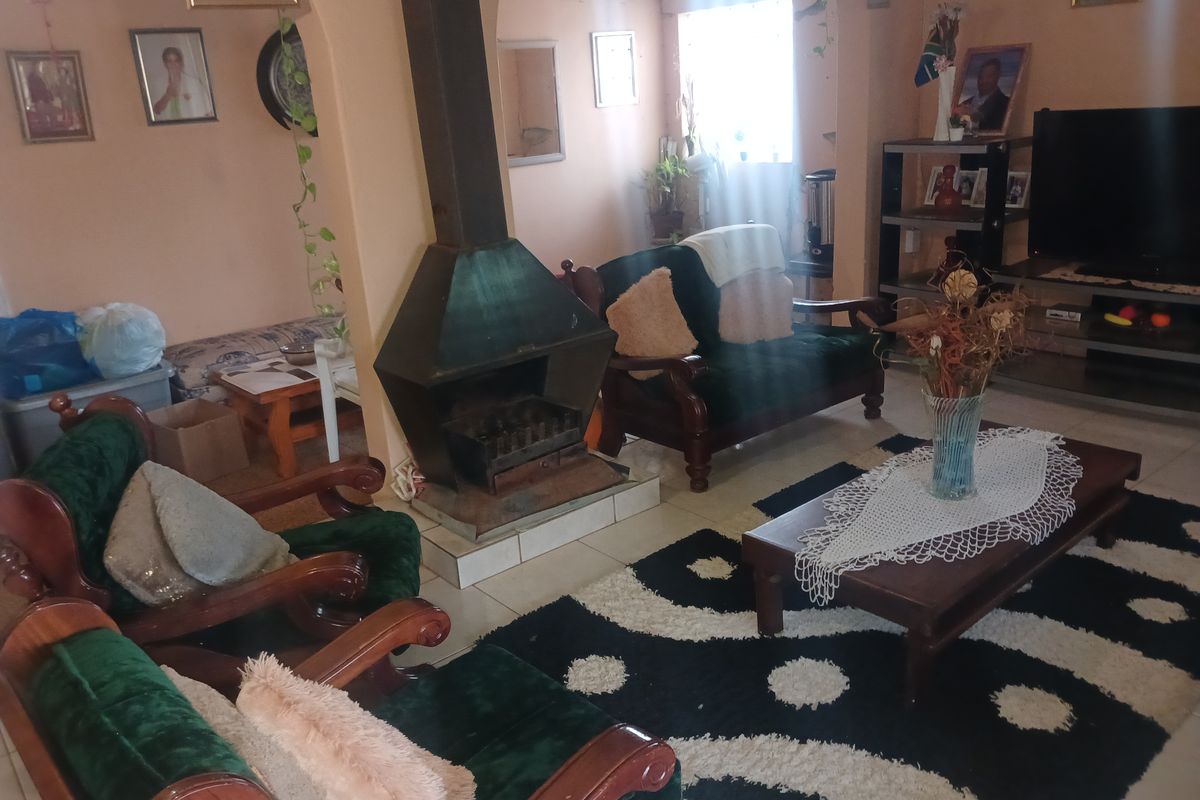 A cozy living room featuring a central freestanding fireplace, tiled flooring, and an open archway leading to an adjacent space.
