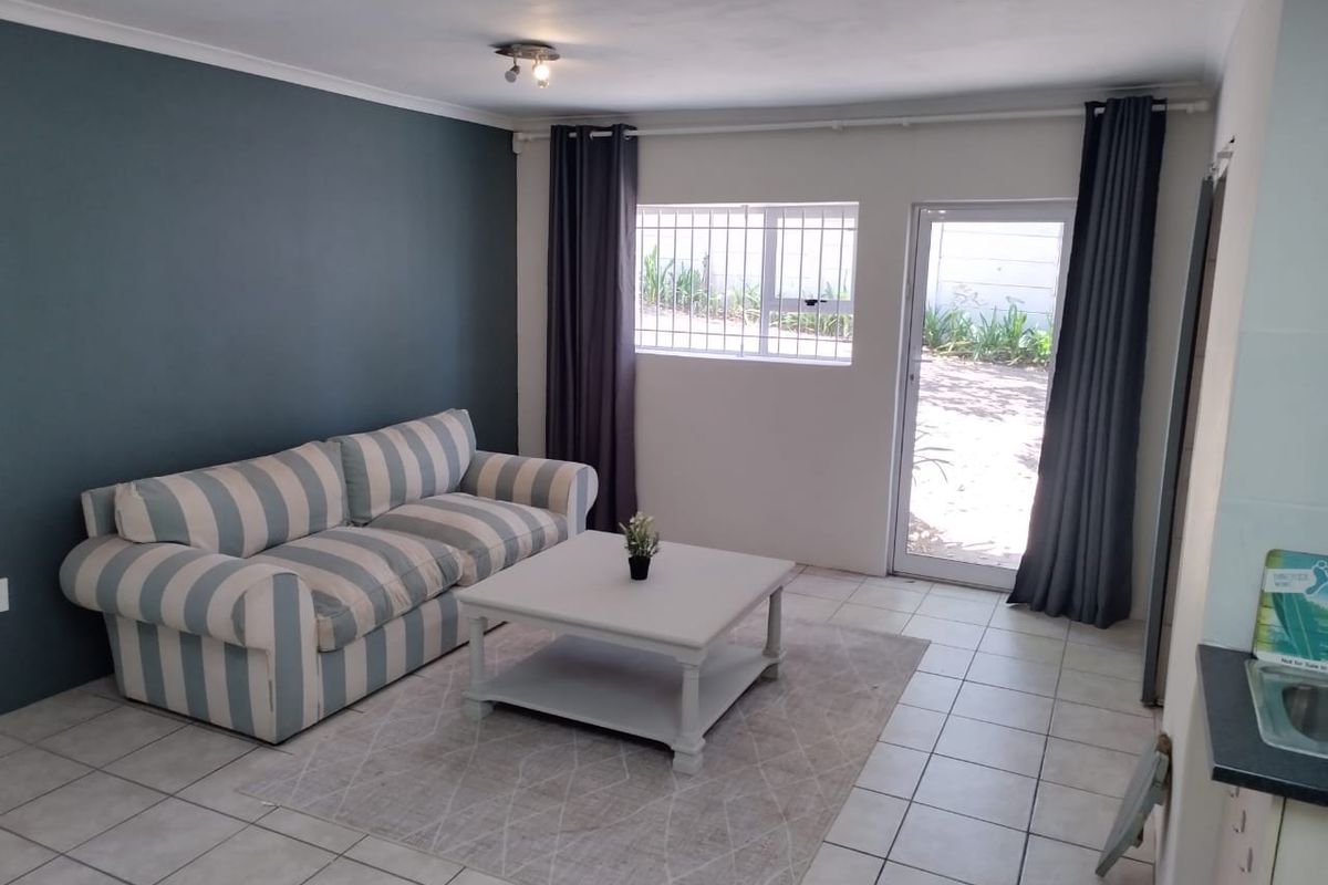 Open plan living area featuring tiled flooring, an accent wall, and direct access to the exterior through a glass panel door.