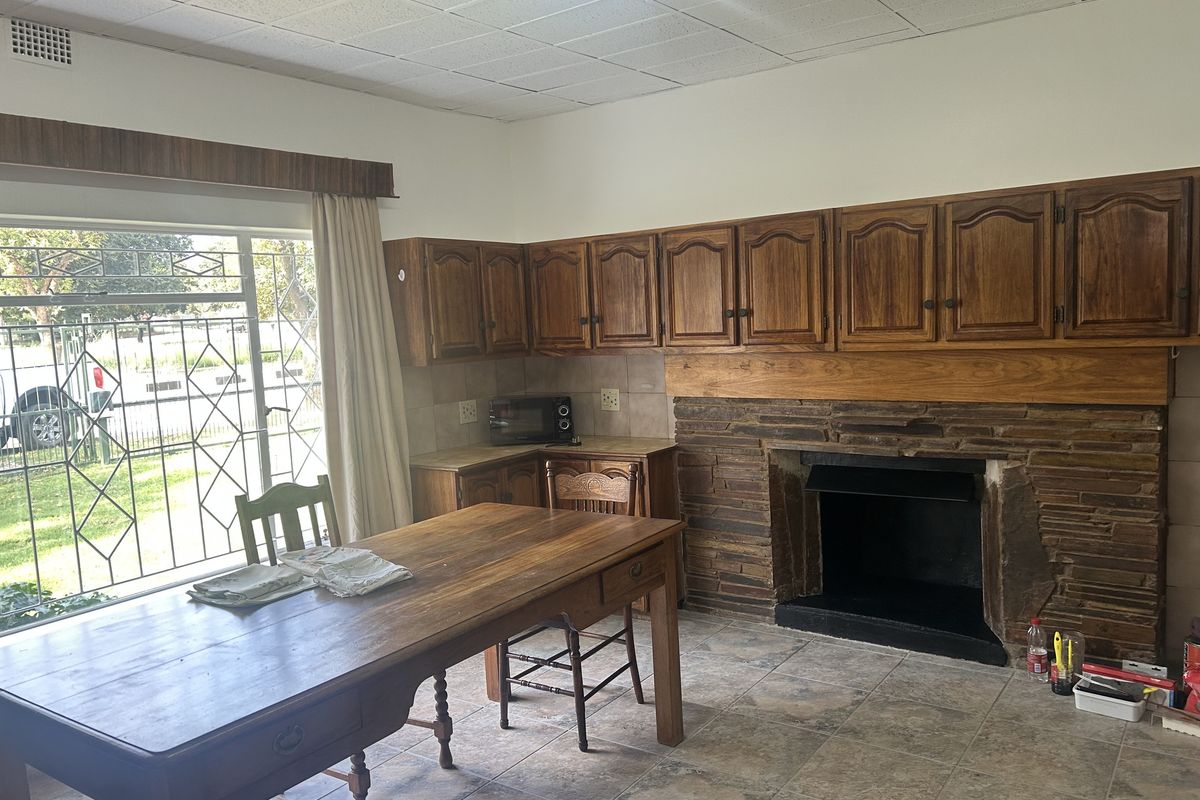 Living area featuring a stone fireplace, built-in wooden cabinetry, and tiled flooring with direct access to the exterior through a security gate.