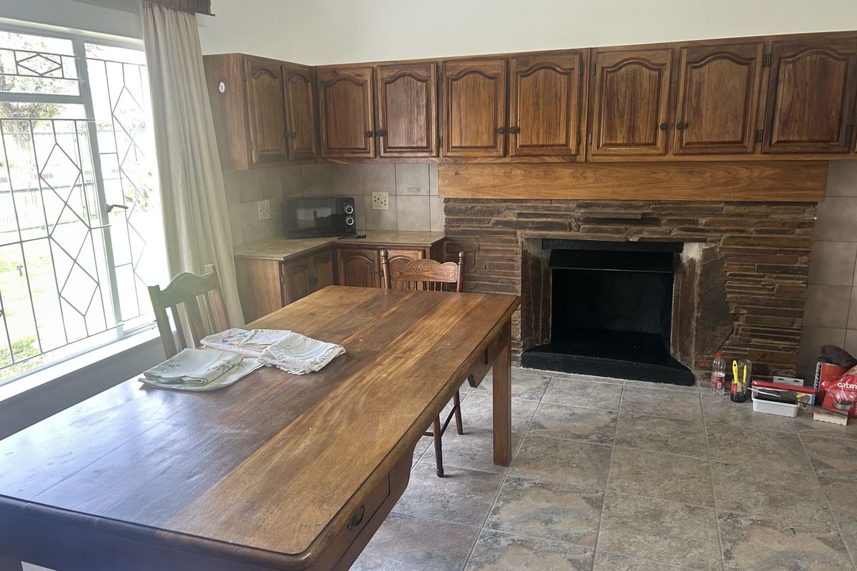 A kitchen area featuring wooden cabinetry, a stone fireplace, and tiled flooring, offering a rustic aesthetic with potential for modernization.