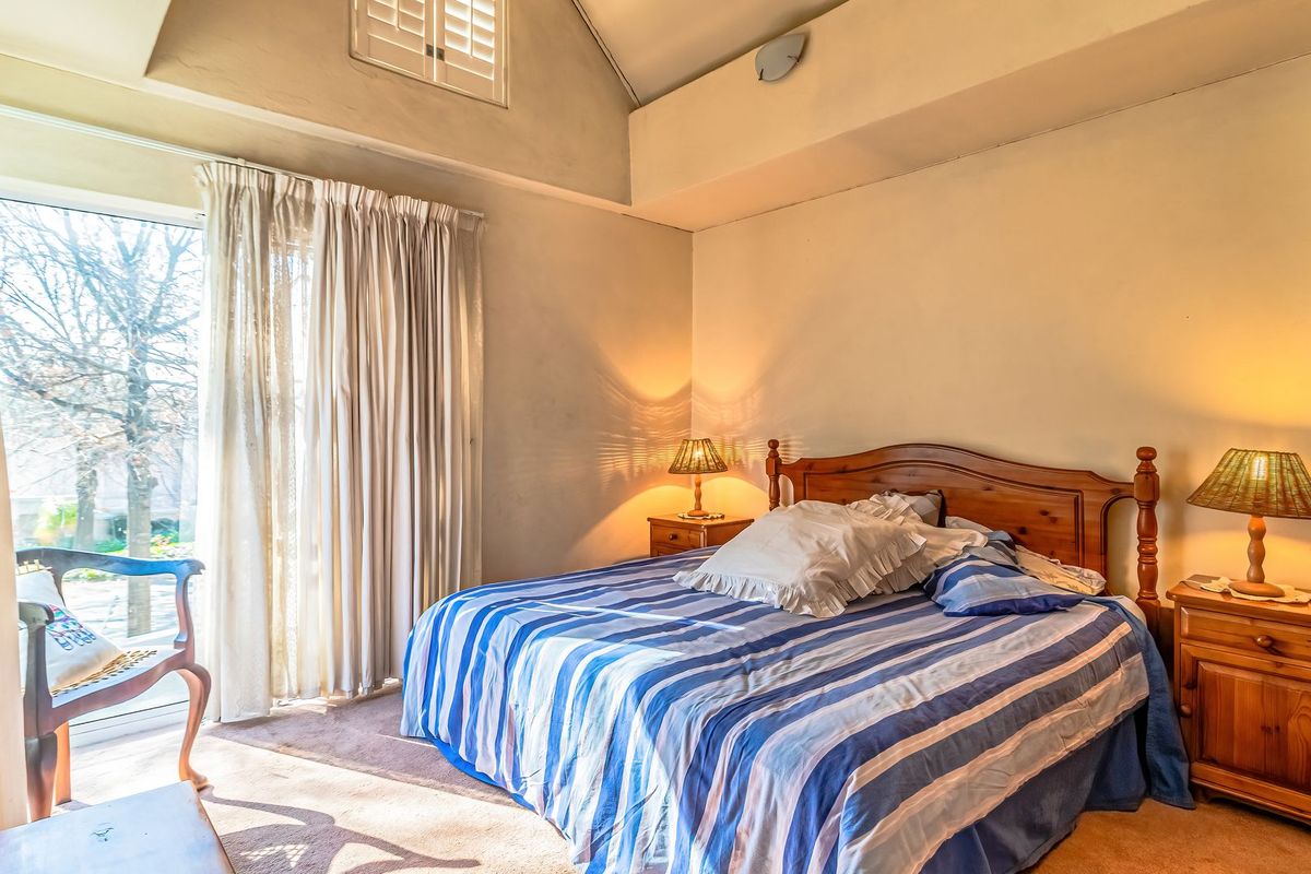 A bedroom featuring a vaulted ceiling, carpeted flooring, and a sliding glass door providing natural light and garden access.