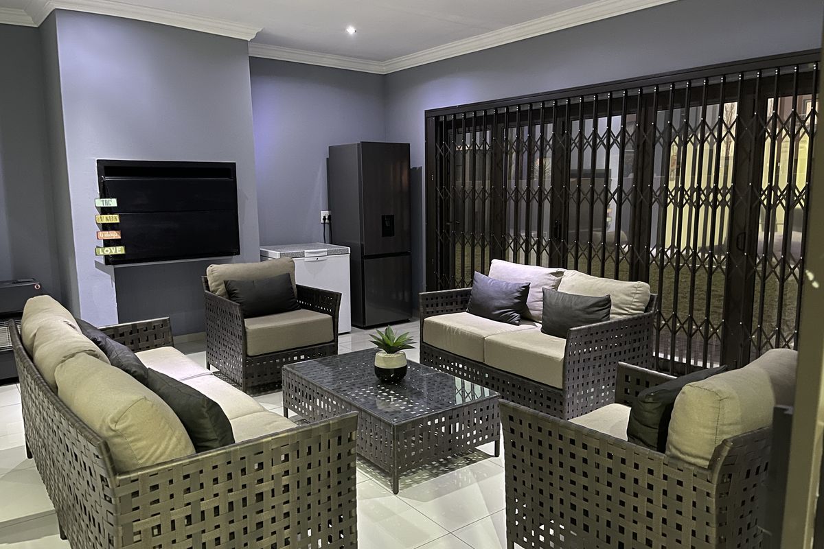 A modern living room featuring tiled floors, recessed lighting, and large sliding glass doors with security gates, providing a clean and contemporary aesthetic.