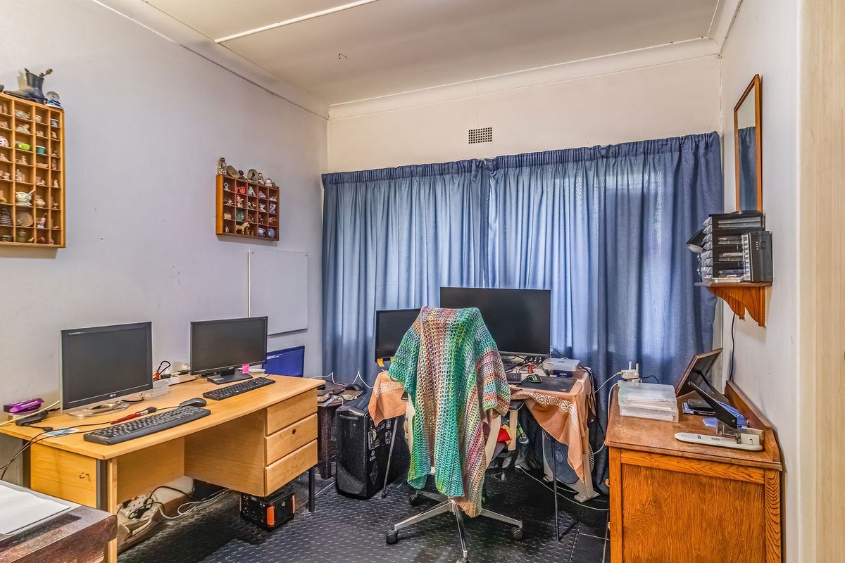 A functional bedroom space featuring a built-in wardrobe, coving, and neutral wall finishes, currently utilized as a home office.
