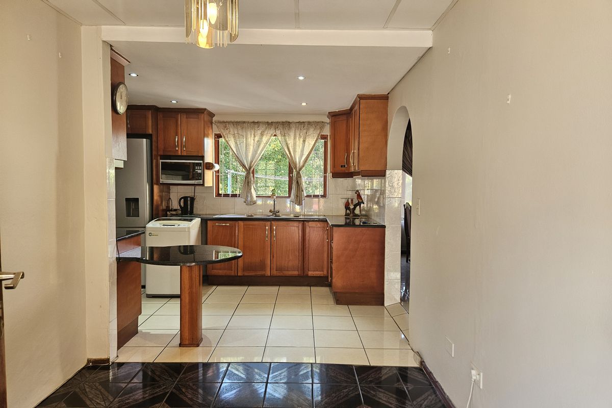A functional kitchen featuring wooden cabinetry, granite countertops, a breakfast bar, and tiled flooring, offering a classic layout with potential for modern updates.