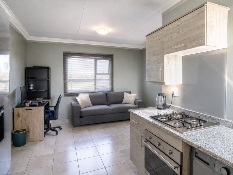 Open-plan living area featuring a modern kitchen with granite countertops, gas hob, built-in oven, and tiled flooring throughout.