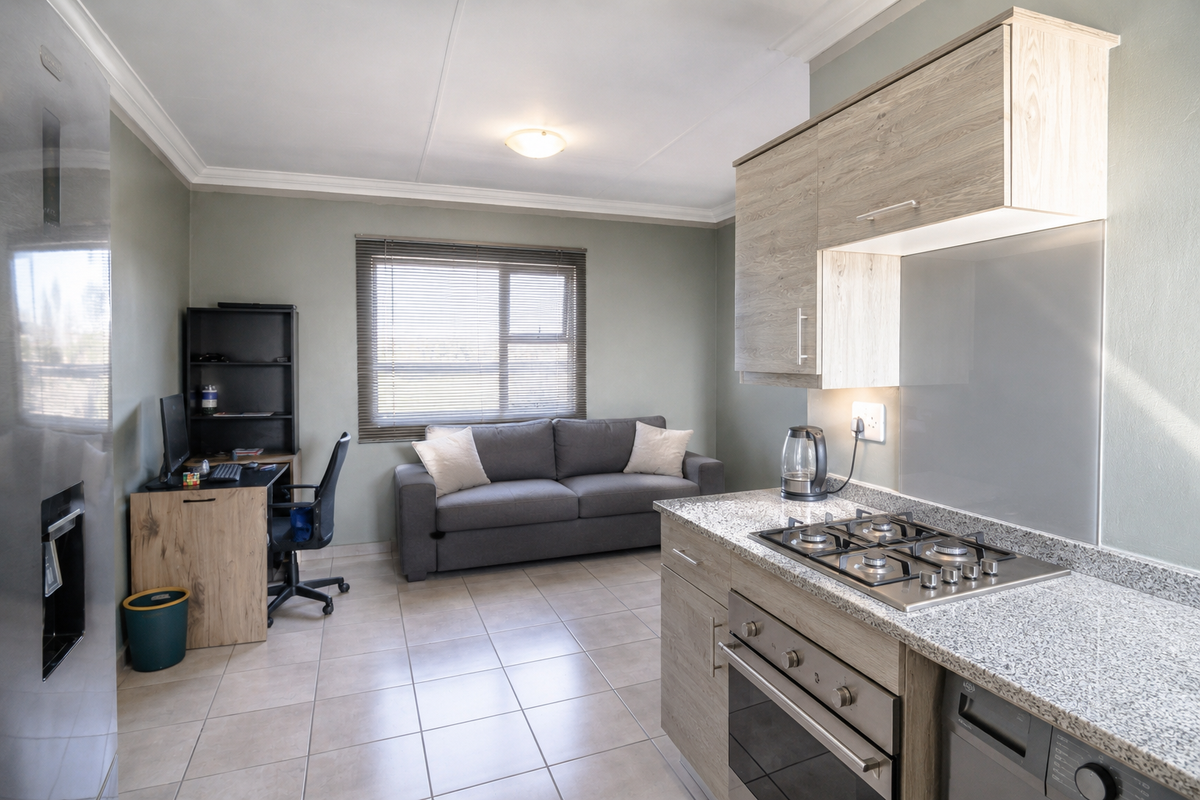 Open-plan living area featuring a modern kitchen with granite countertops, gas hob, built-in oven, and tiled flooring throughout.