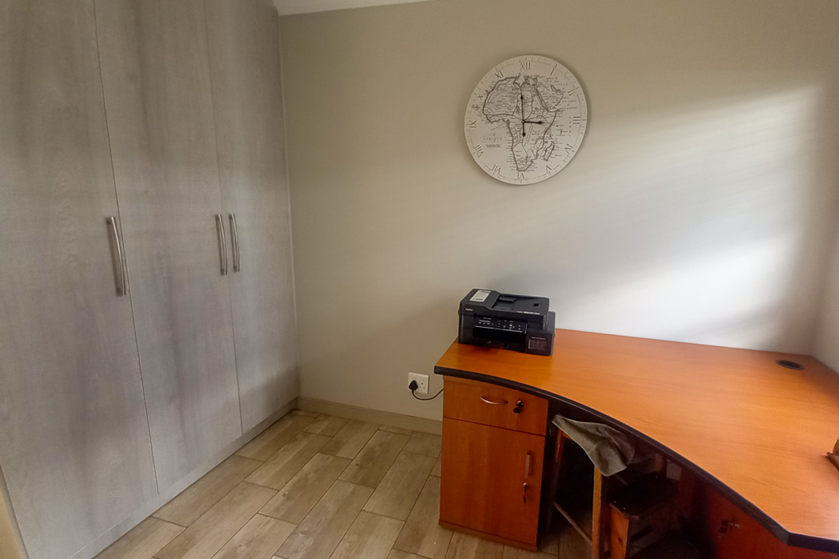 A functional bedroom featuring built-in floor-to-ceiling wardrobes and wood-look tile flooring, providing ample storage and a neutral aesthetic.