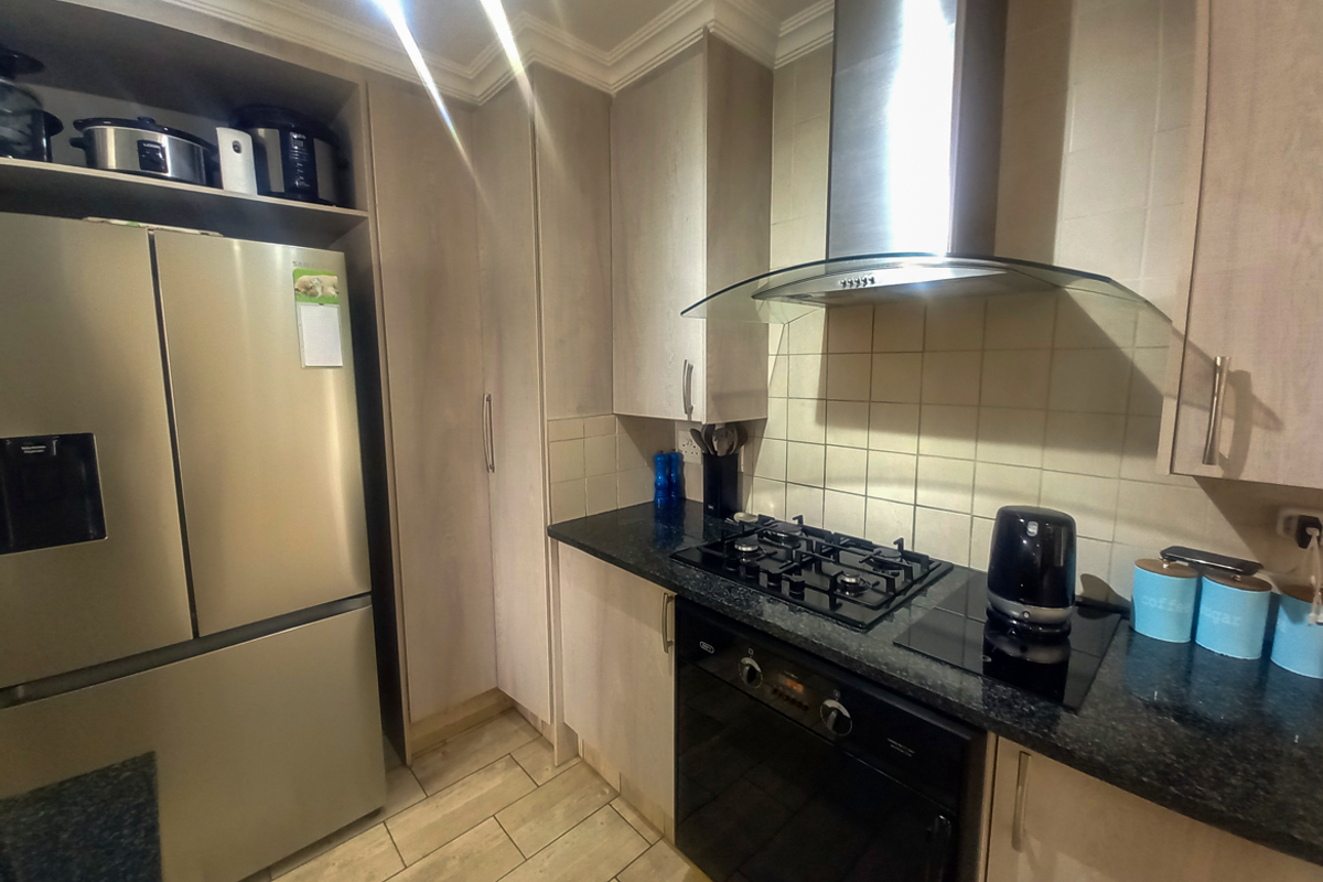 A functional kitchen featuring built-in cabinetry, a gas hob, an integrated extractor fan, and a modern oven with tiled splashbacks.