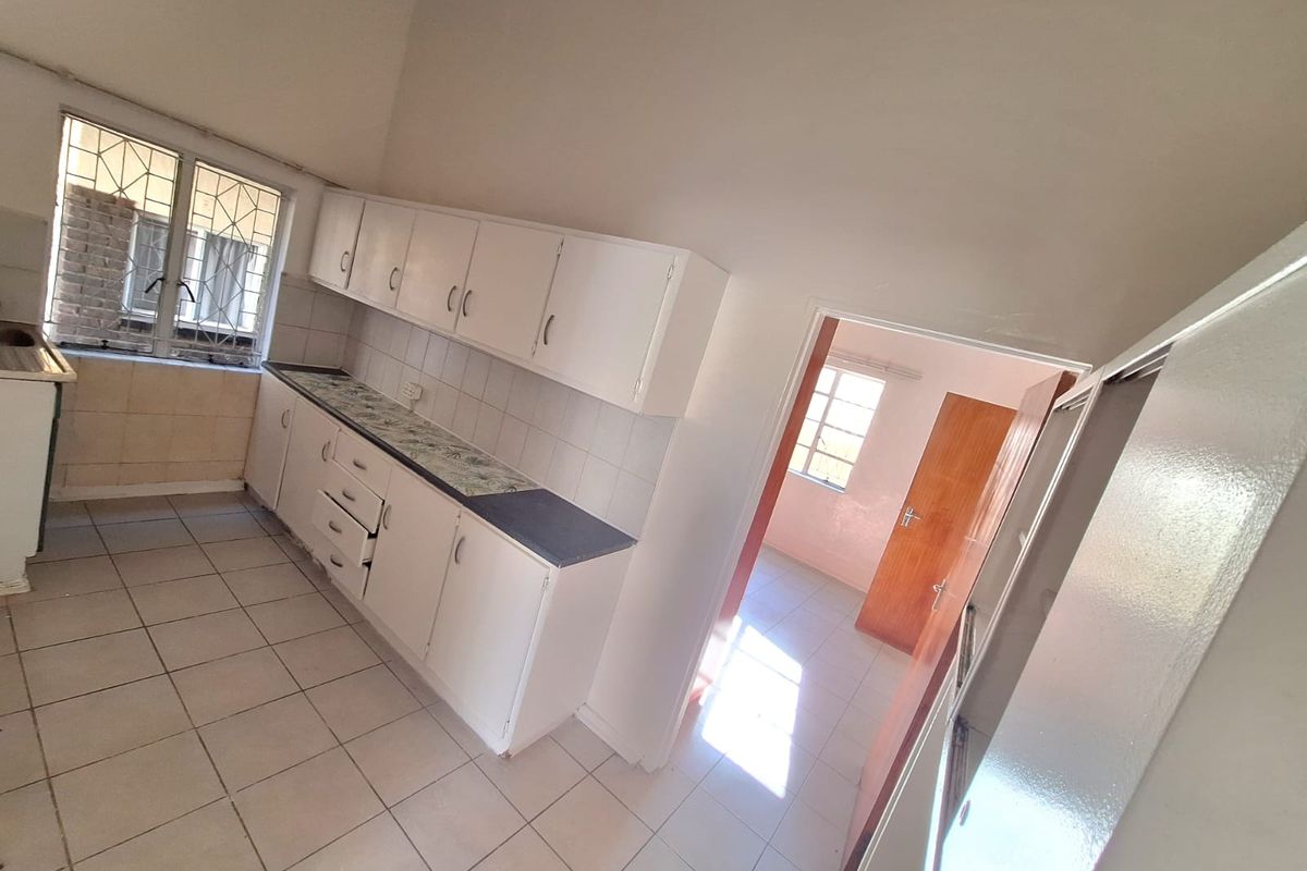 A functional kitchen featuring white built-in cabinetry, tiled flooring, and a tiled backsplash, offering a blank canvas for modern updates.