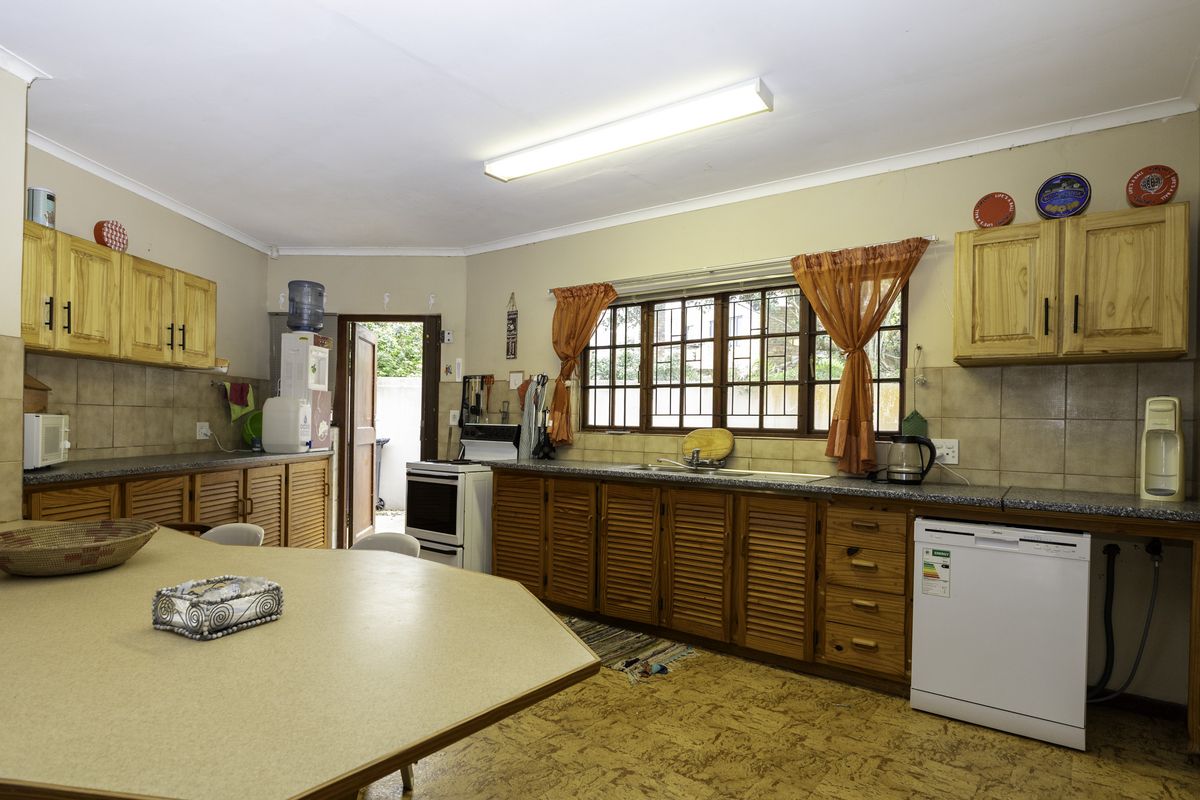A functional kitchen featuring louvered timber cabinetry, laminate countertops, and a tiled backsplash, offering potential for modernization and aesthetic updates.
