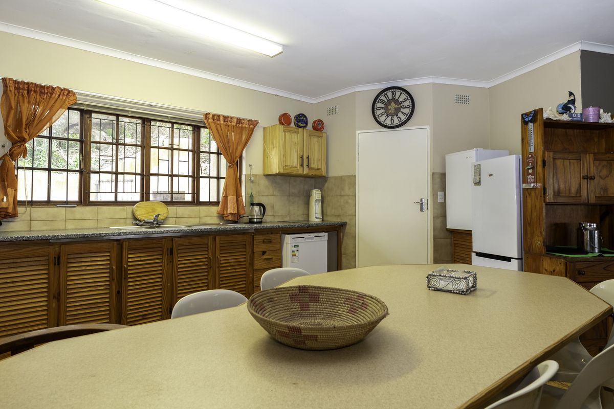 A functional kitchen featuring louvered timber cabinetry, tiled splashbacks, and laminate countertops, offering a dated aesthetic with potential for modern renovation.