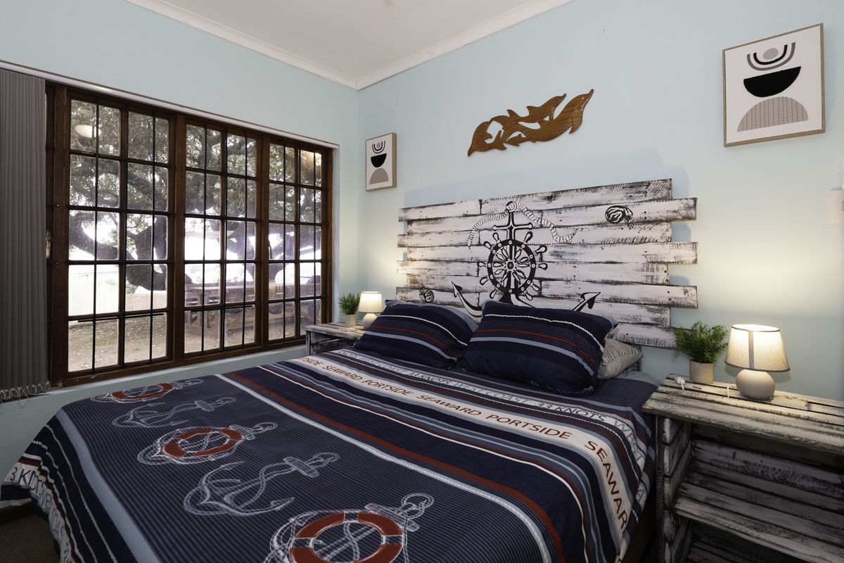 A cozy bedroom featuring timber-framed windows and light blue walls, offering a comfortable and well-maintained space.