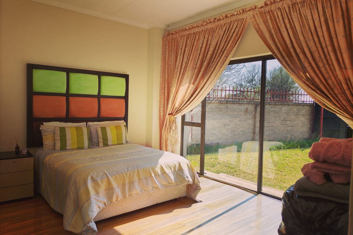 A bedroom featuring laminate flooring and a large sliding glass door providing direct access to the rear garden area.