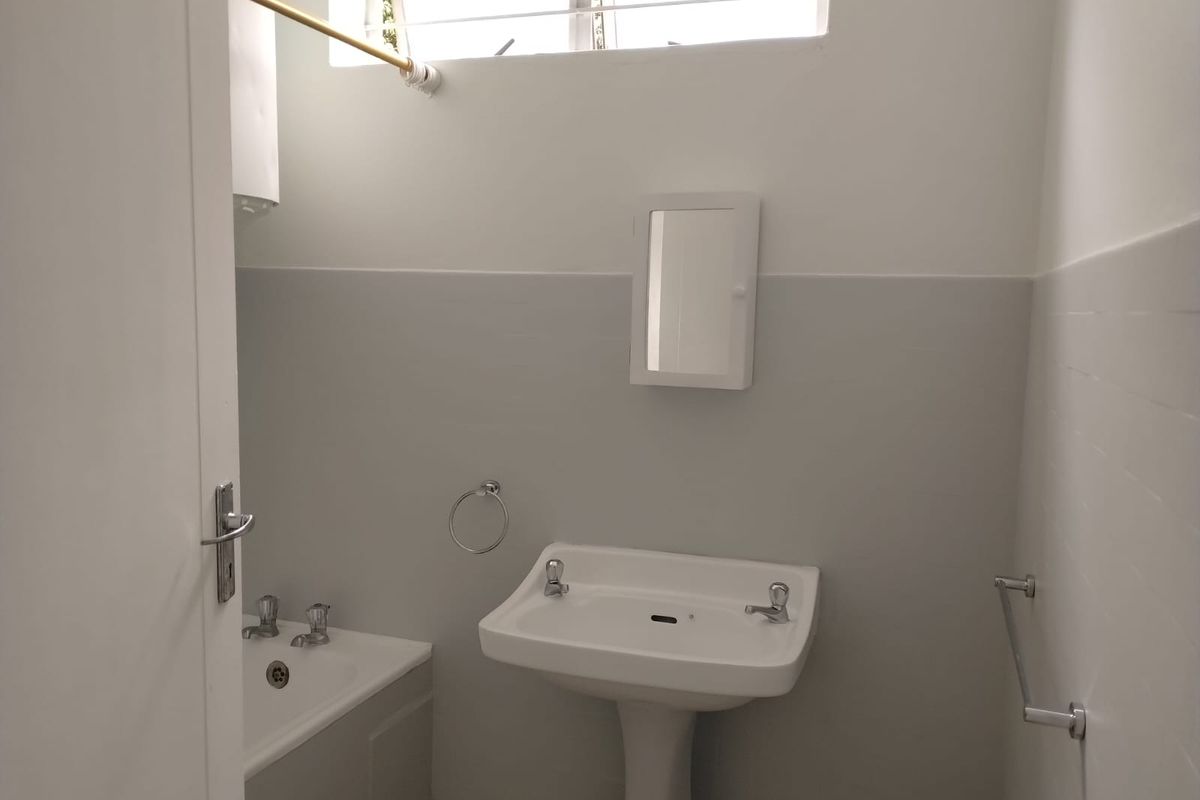 A functional bathroom featuring a pedestal basin, bathtub, and wall-mounted medicine cabinet with neutral wall finishes.