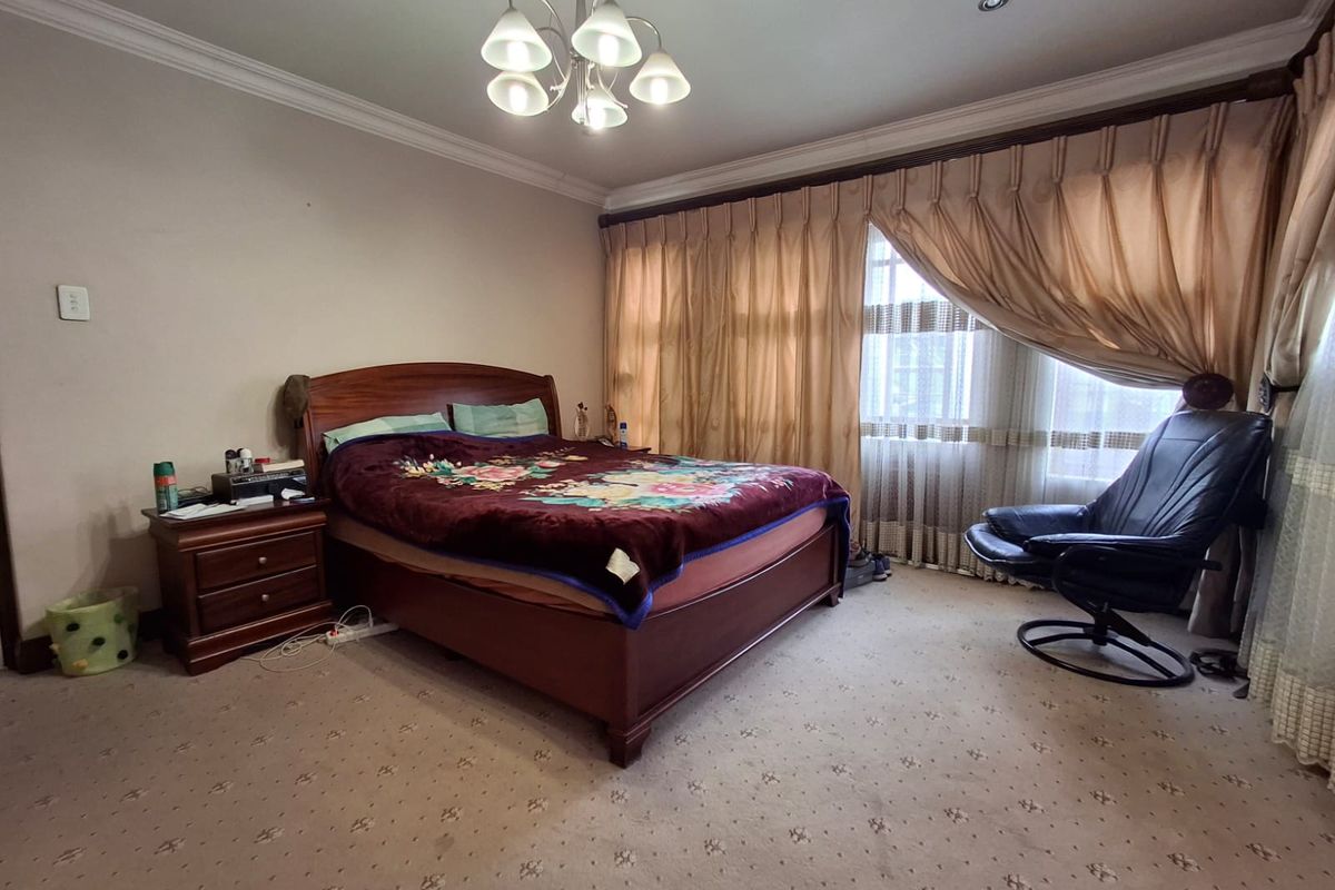 A spacious bedroom featuring crown molding, recessed lighting, a central chandelier, and carpeted flooring.