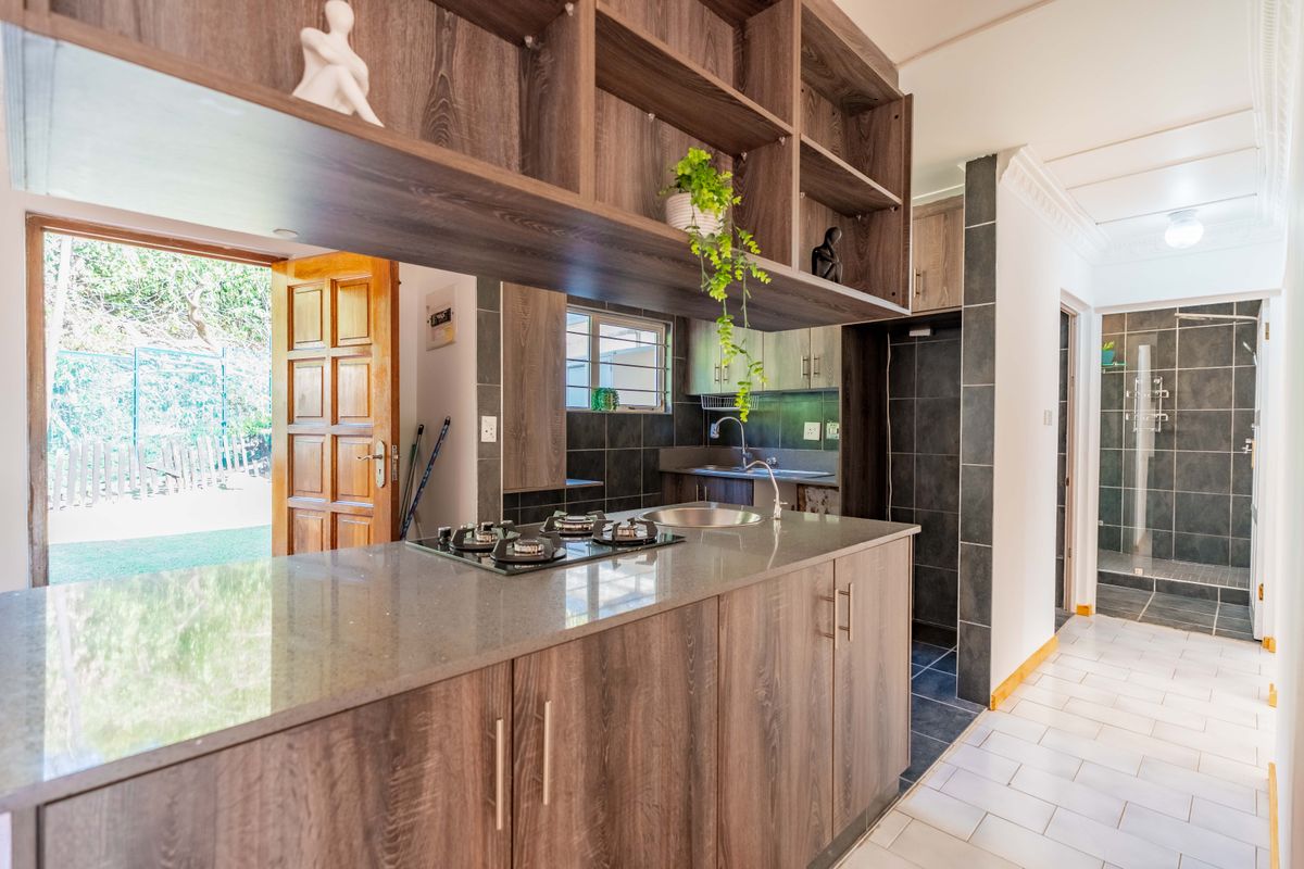 Modern kitchen featuring dark wood cabinetry, stone countertops, integrated gas hob, and direct access to the outdoor area.