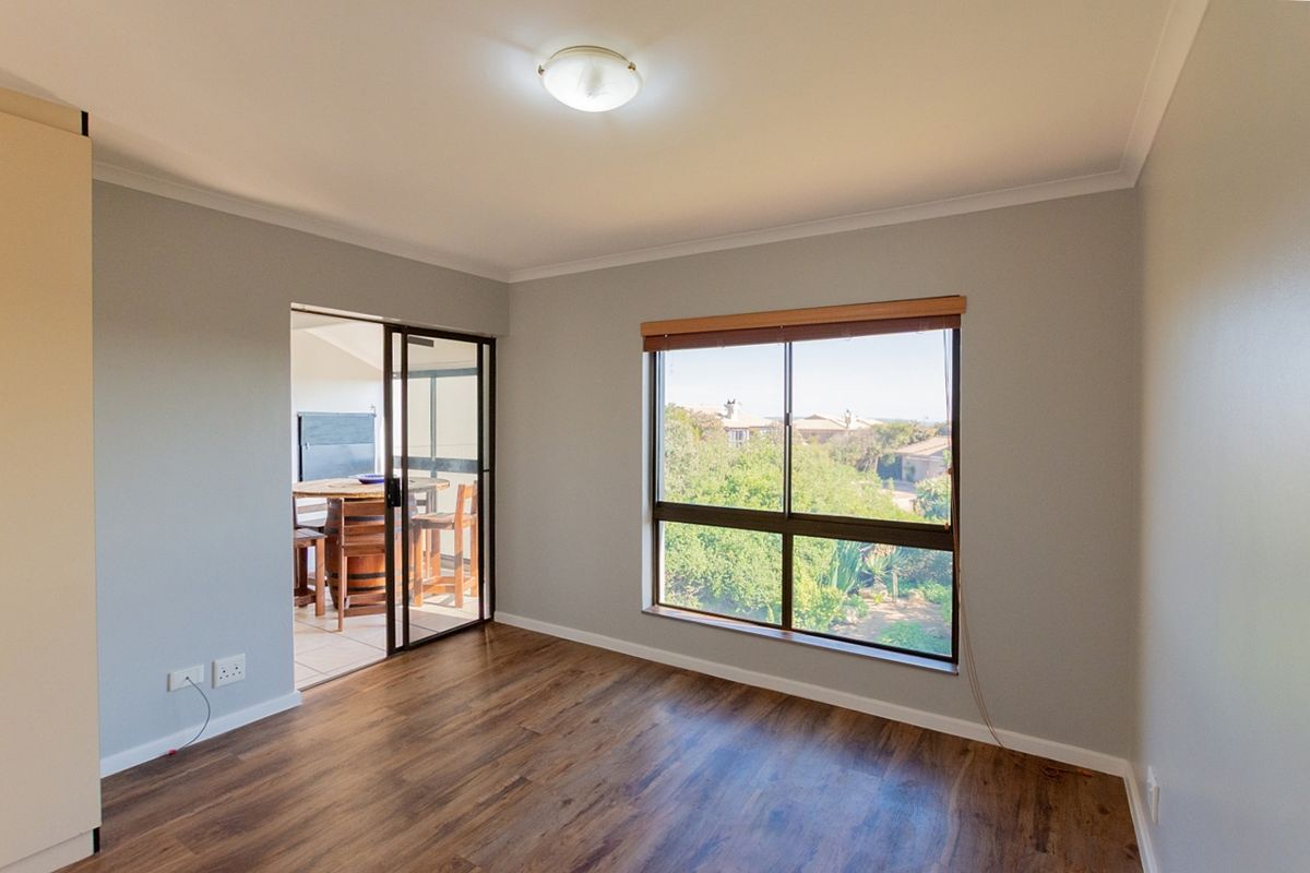 A bright, empty bedroom featuring laminate flooring, a built-in cupboard, and a sliding glass door leading to an outdoor patio area.