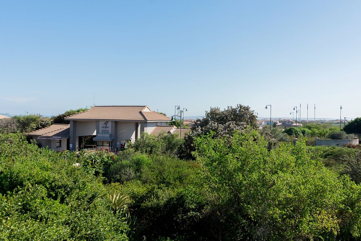 An elevated view of the property's rear exterior, featuring a tiled roof structure surrounded by mature trees and landscaped greenery.