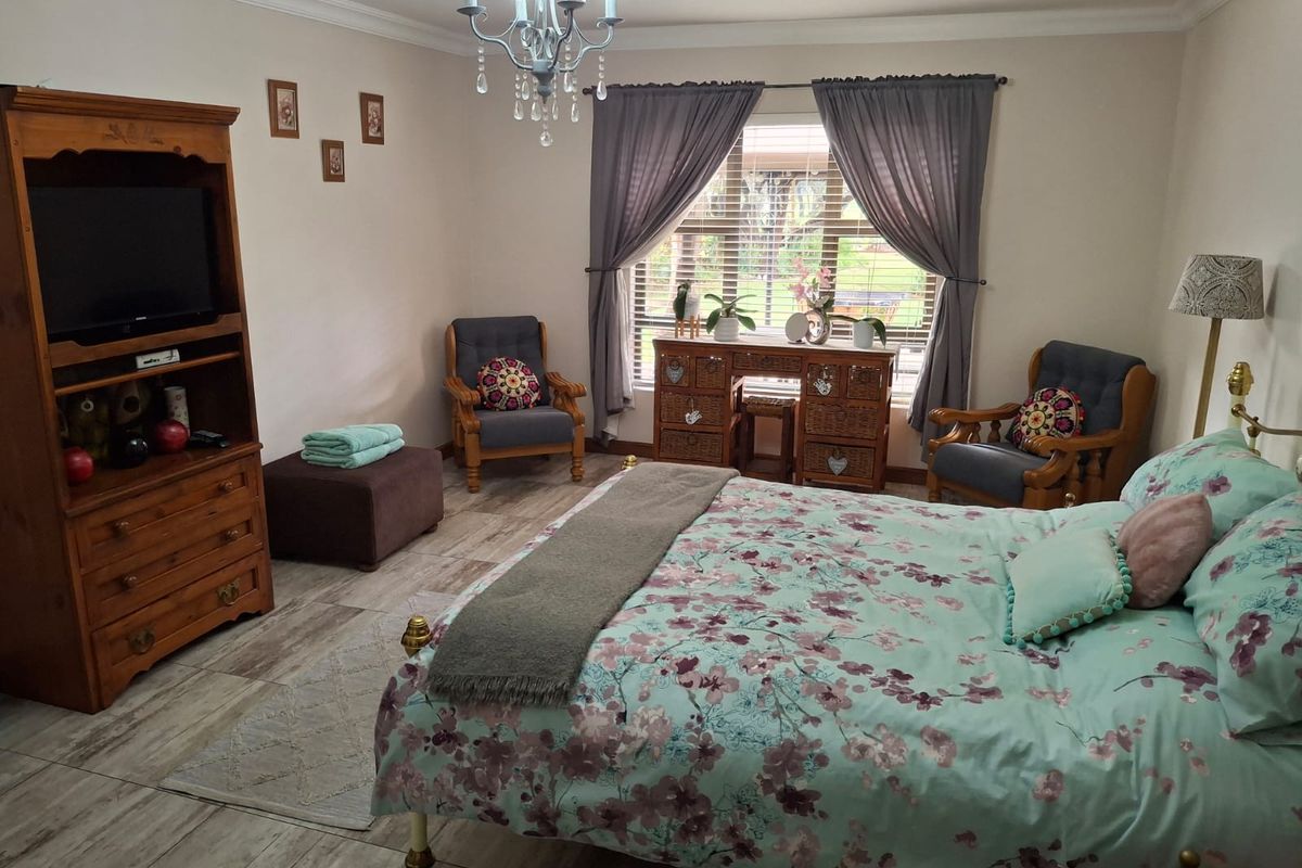 A well-maintained bedroom featuring tiled flooring, crown molding, and a central chandelier, providing a comfortable and functional living space.