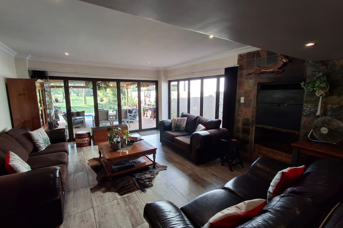 Spacious living room featuring tiled flooring, a stone-clad built-in fireplace, and large stacking glass doors providing seamless access to the outdoor patio area.
