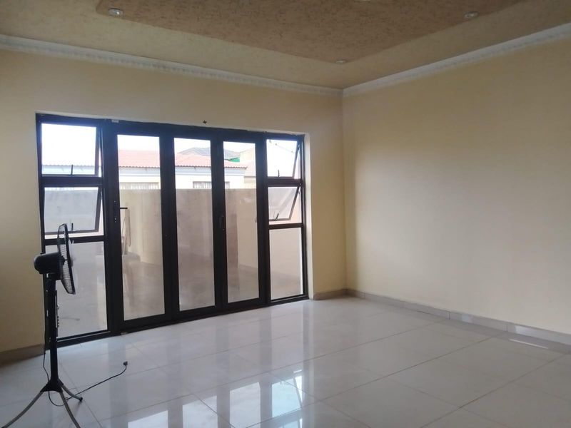 Spacious living area featuring polished tiled flooring, recessed ceiling detail, and large aluminium stacker doors providing access to the exterior.