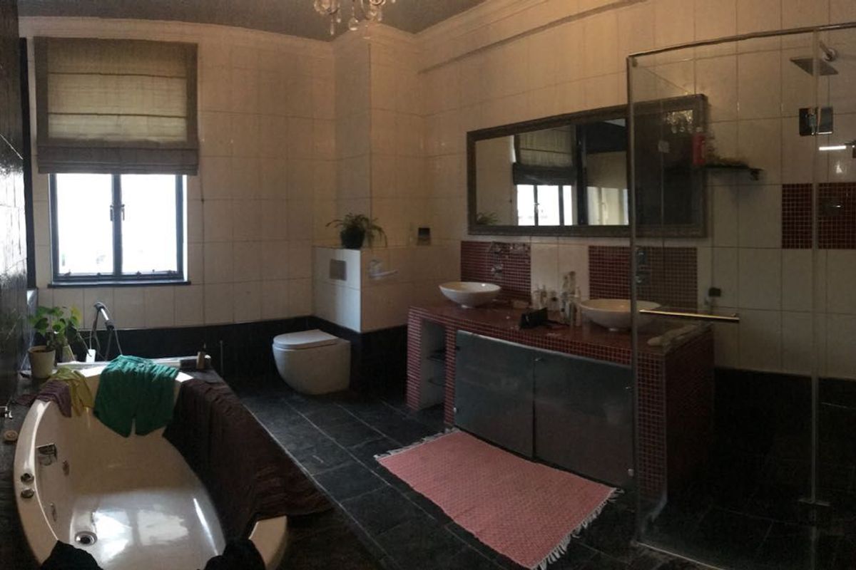 Spacious bathroom featuring a freestanding bathtub, double vanity with built-in cabinetry, wall-mounted toilet, and a separate glass-enclosed shower with tiled finishes.