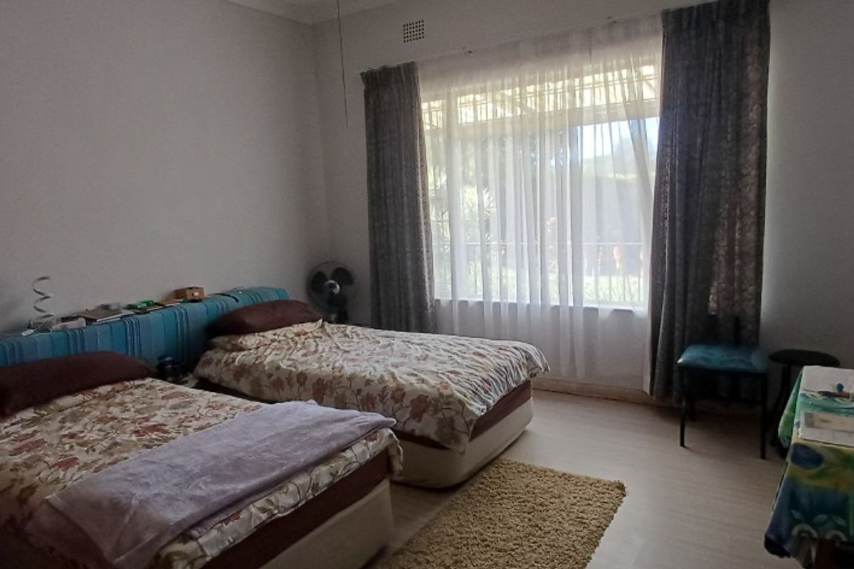 A functional bedroom featuring laminate flooring and a large window that allows for natural light.
