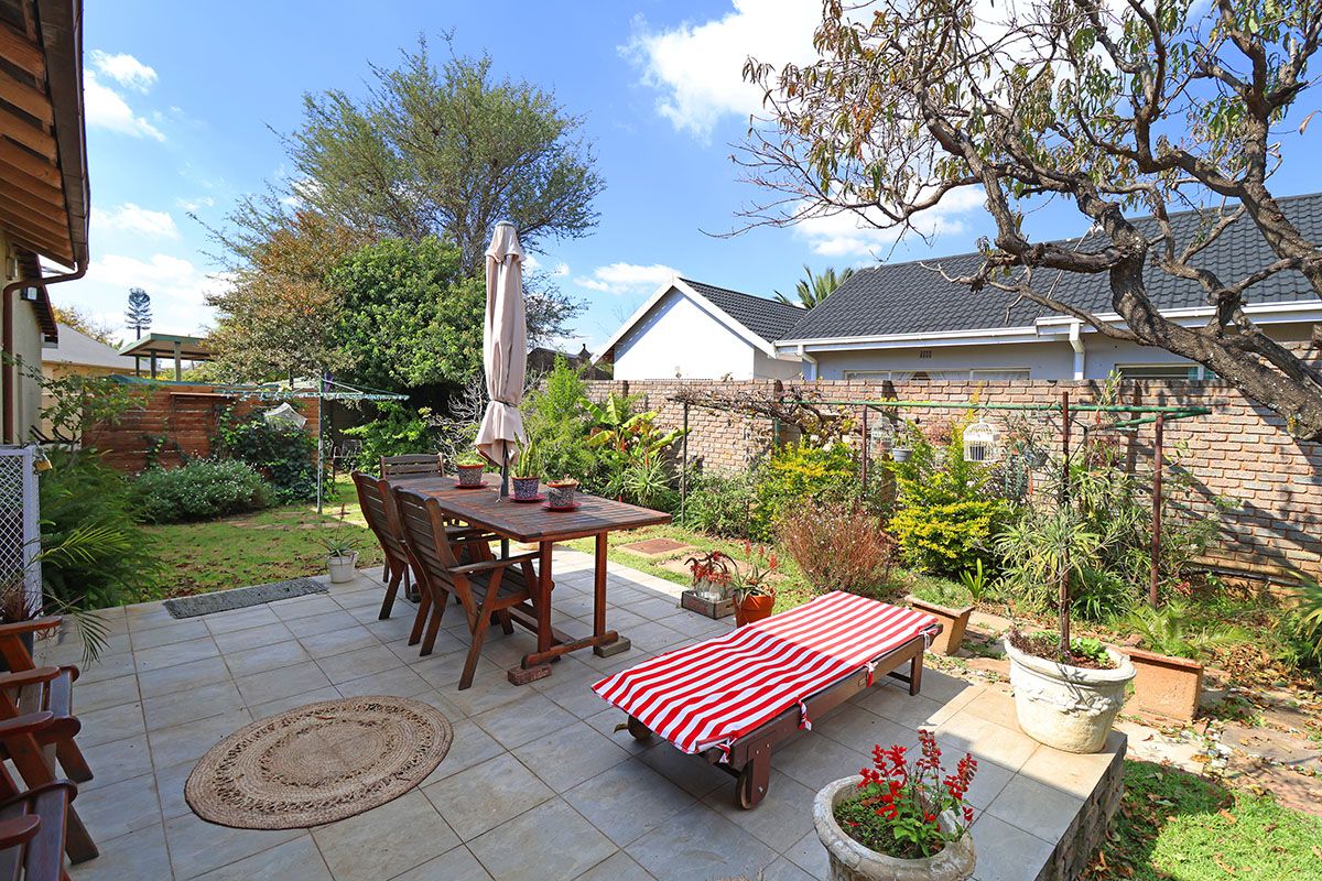 A private rear garden featuring a paved patio area, established landscaping, and a brick boundary wall, ideal for outdoor relaxation and entertaining.