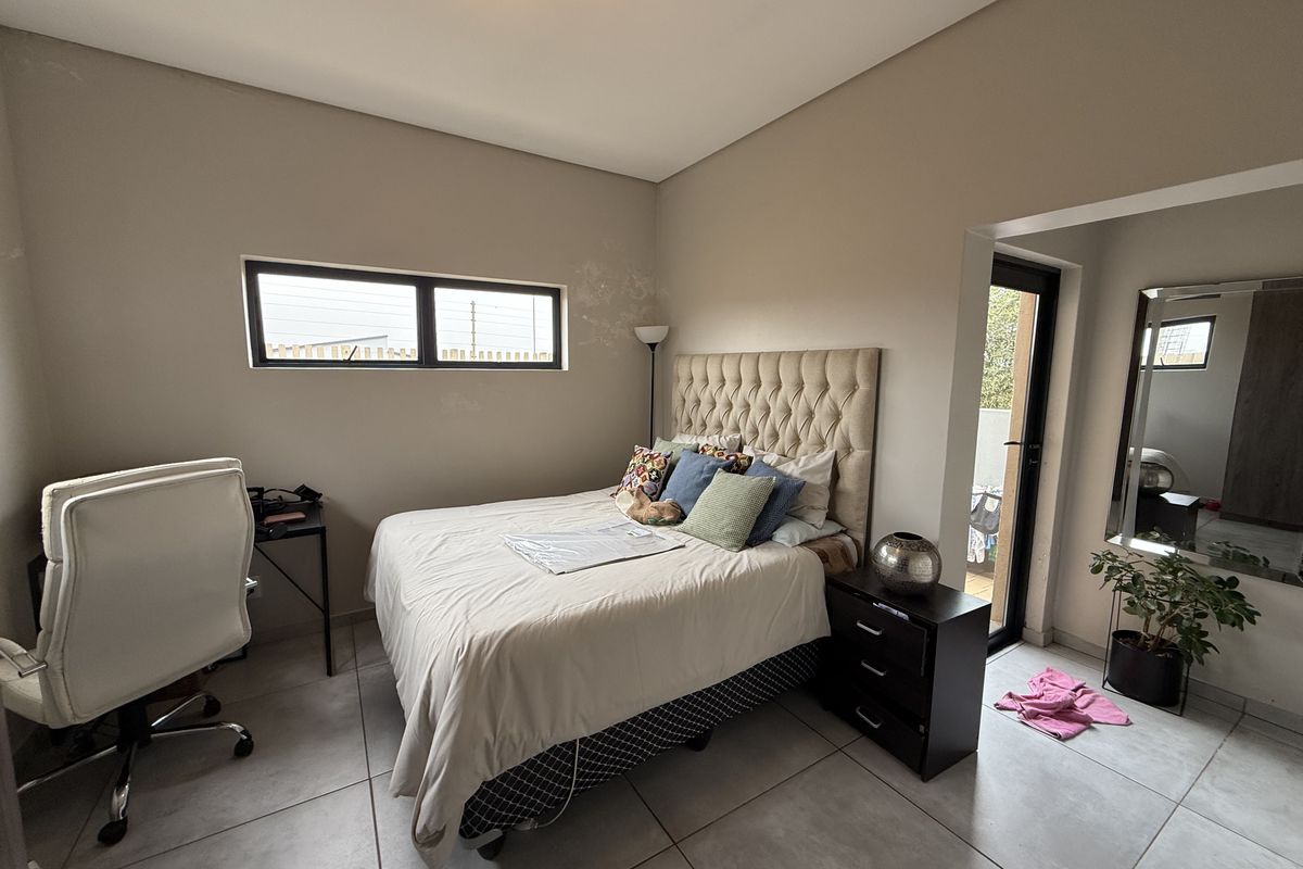 A bedroom featuring tiled flooring, neutral wall tones, and direct access to an outdoor area through a glass door.