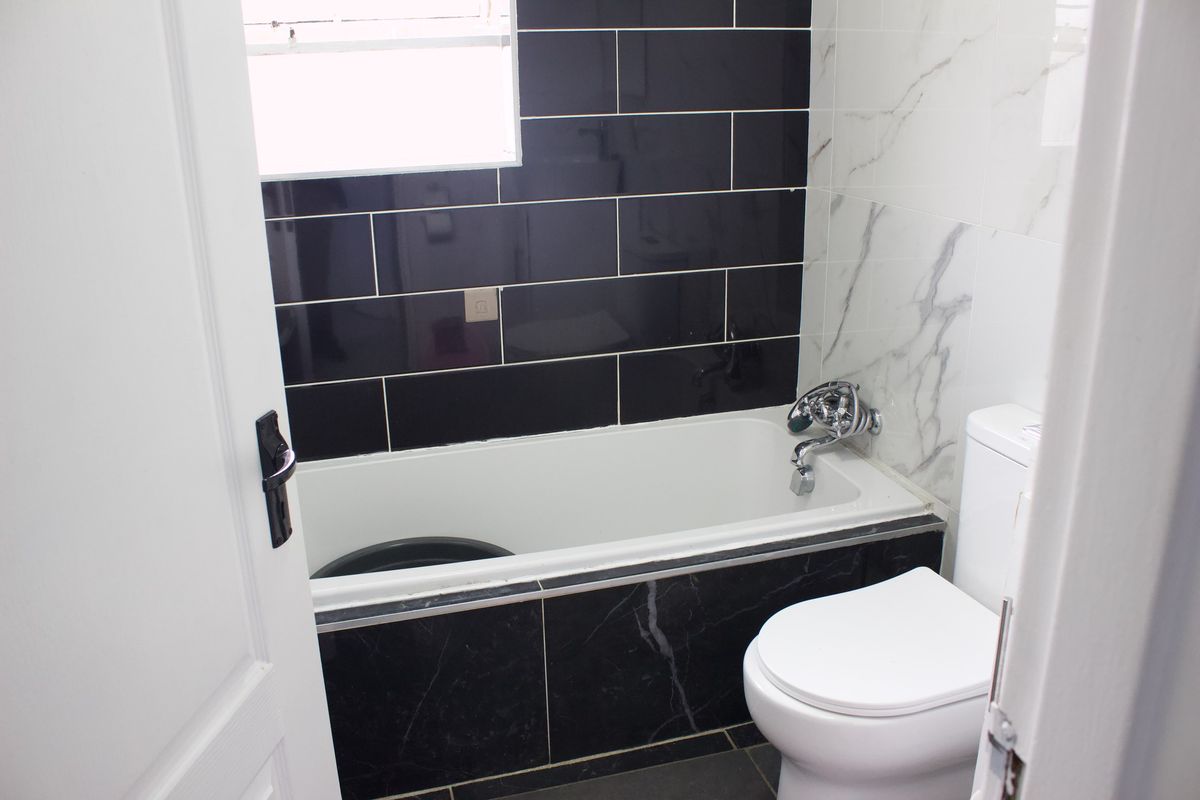 A modern bathroom featuring a bathtub, toilet, and contrasting black and white marble-effect wall tiling.