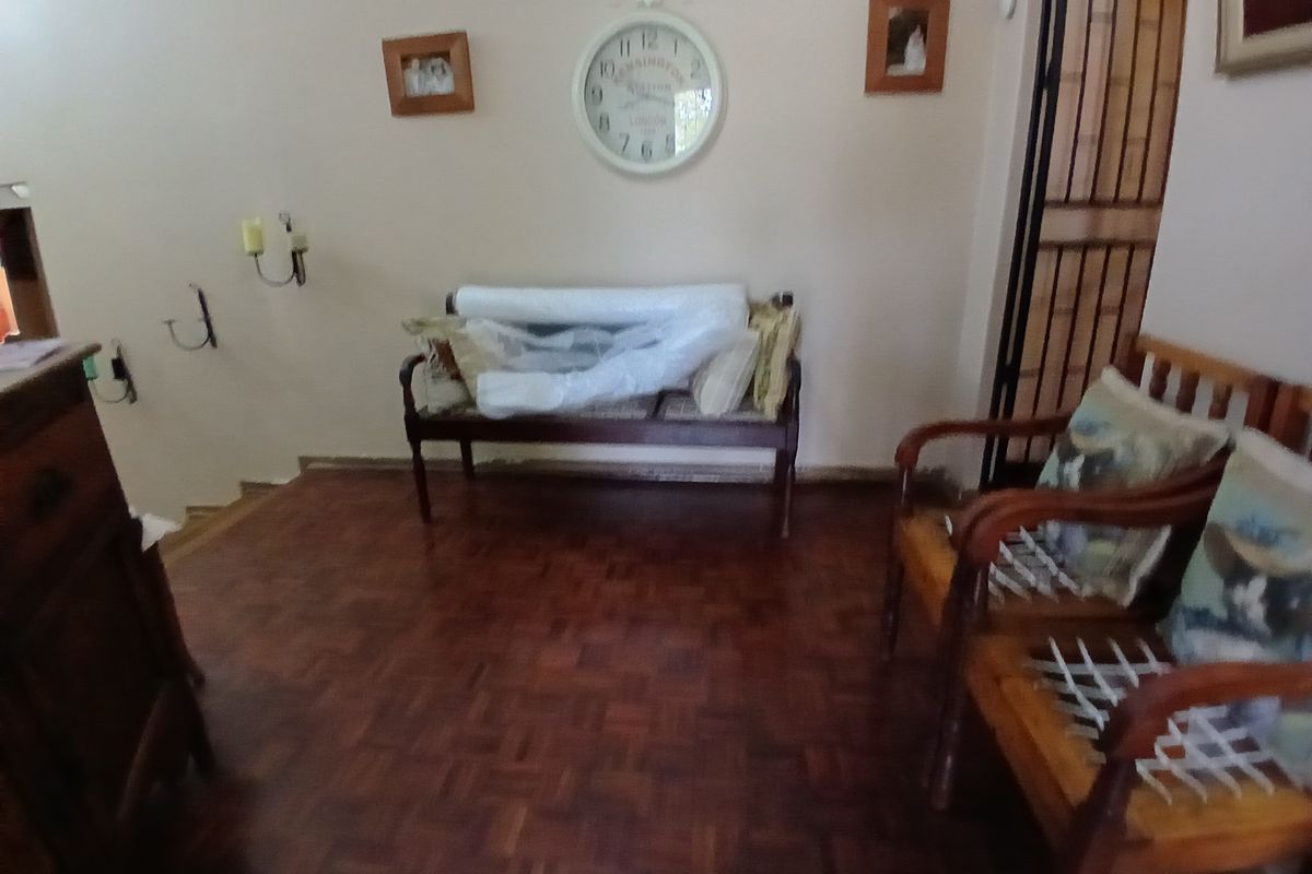 A living area featuring traditional parquet flooring and a security gate, providing a functional space with potential for modern updates.