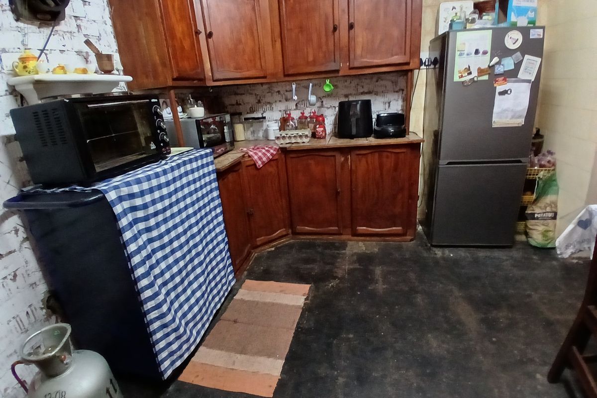 A dated kitchen featuring wooden cabinetry and exposed brick walls, requiring cosmetic updates to improve the overall aesthetic and functionality.