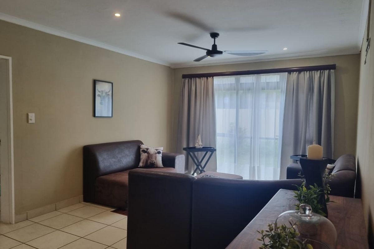 A comfortable living room featuring tiled flooring, recessed ceiling lighting, and a ceiling fan, with direct access to an outdoor patio area.