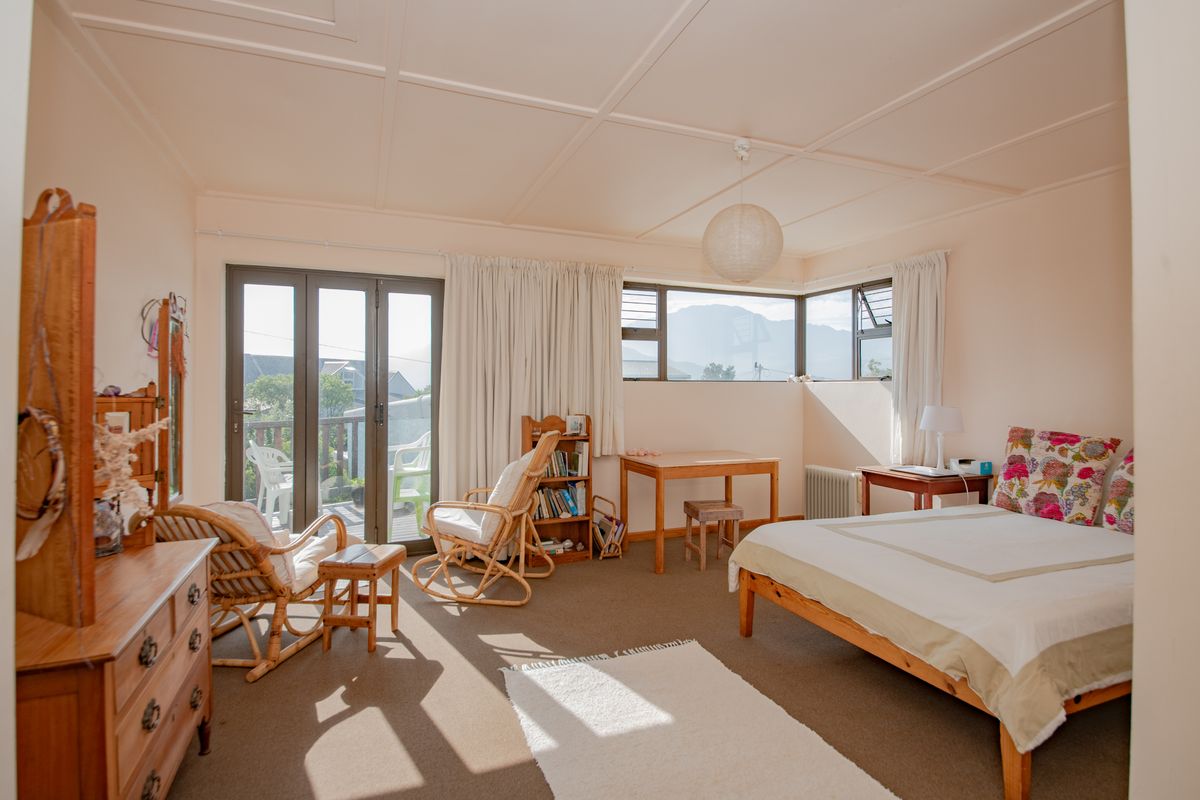 Spacious bedroom featuring corner windows, a radiator, and sliding glass doors providing access to an outdoor balcony area.
