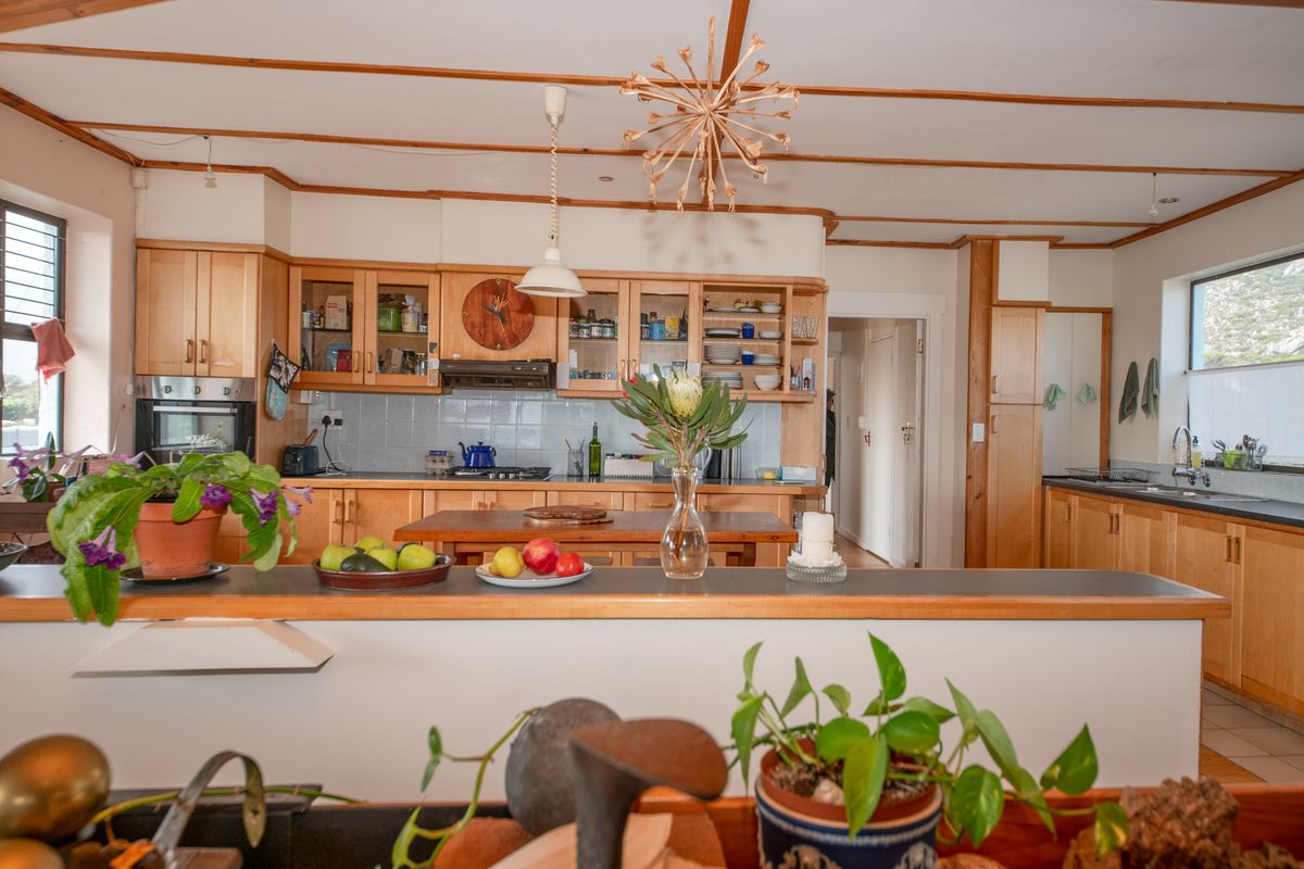 Spacious kitchen featuring light wood cabinetry, integrated appliances, tiled backsplash, and exposed timber ceiling beams, offering a functional and warm cooking environment.