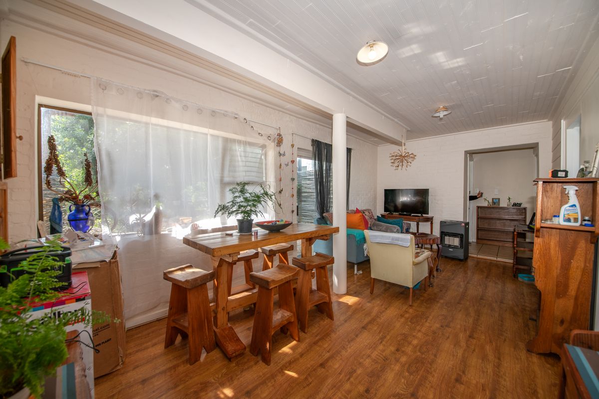 A spacious living area featuring timber flooring, a painted timber ceiling, and a large sliding glass door providing natural light and garden access.